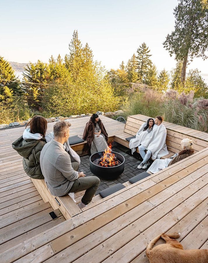 A group of people at a 5-MeO-DMT retreat sitting around a fire pit inset into a modern deck.