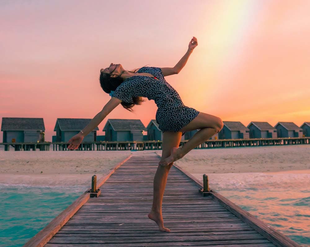 A woman dancing on a dock in the sunset
