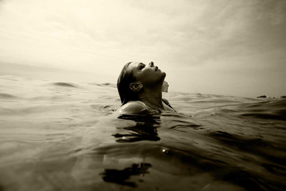 A woman taking a breath while swimming in the ocean.