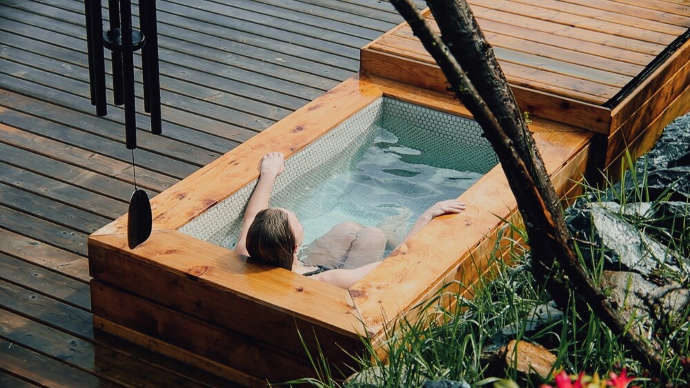 Woman relaxing in cold plunge tub at Enfold Communal